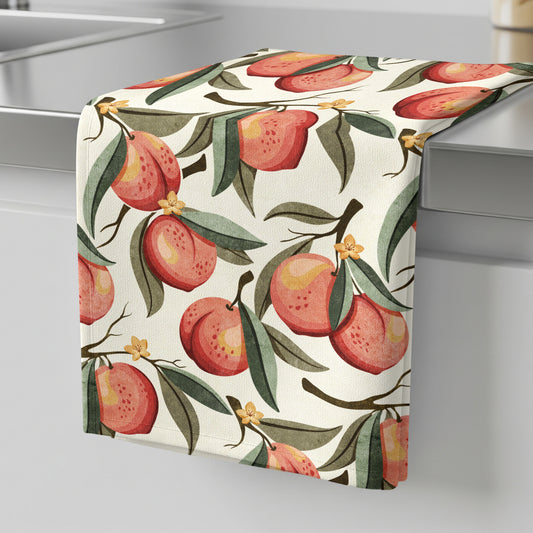 Hand-painted peach tea towel featuring ripe peaches, green leaves, and delicate blossoms on a soft cream background.