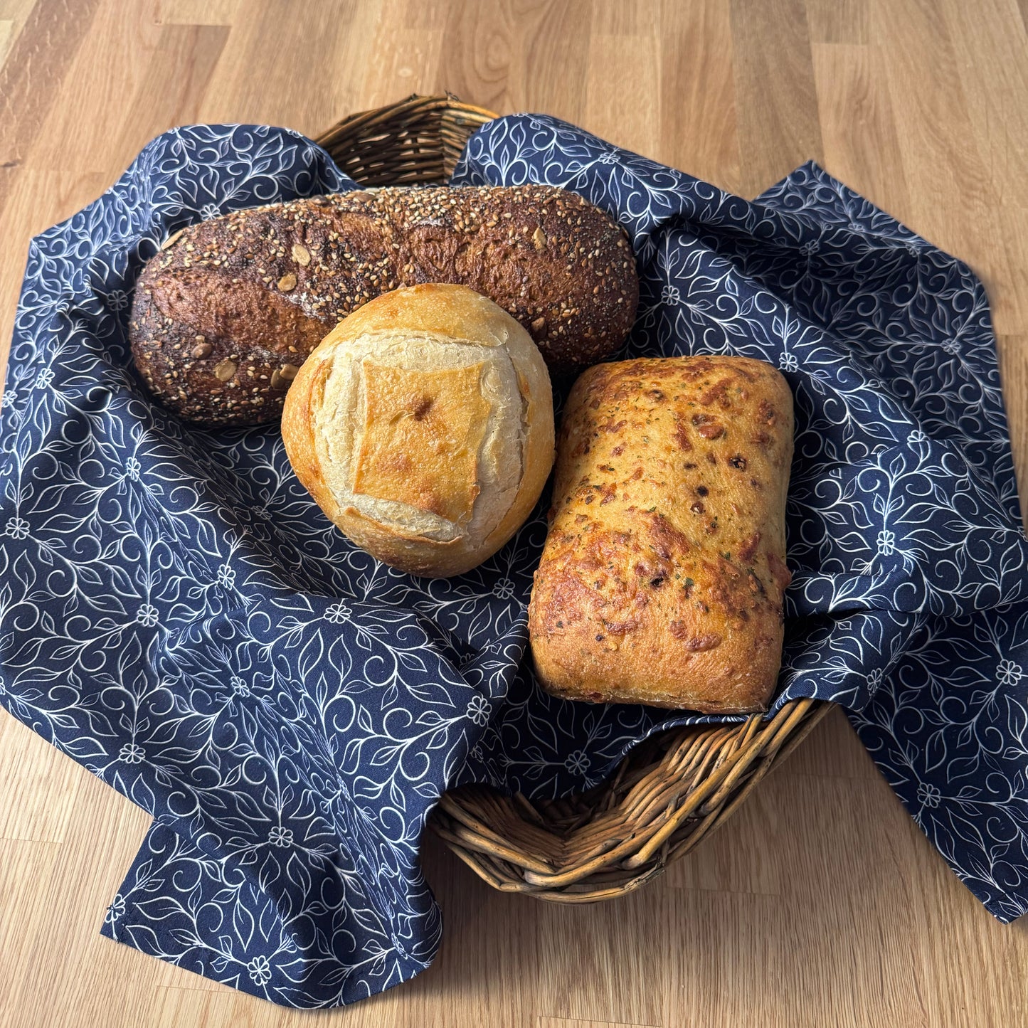 Basket of bread on a wooden surface with a blue patterned cloth