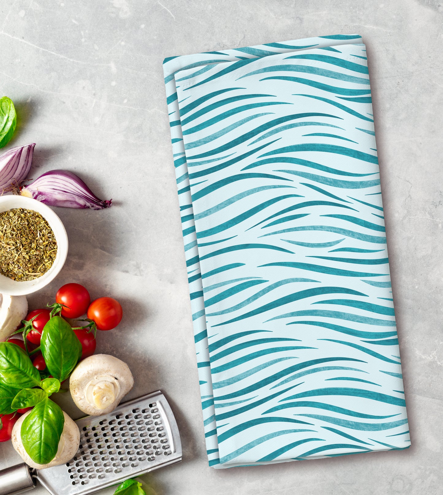 Teal and white patterned towel on a kitchen counter with vegetables and a grater.