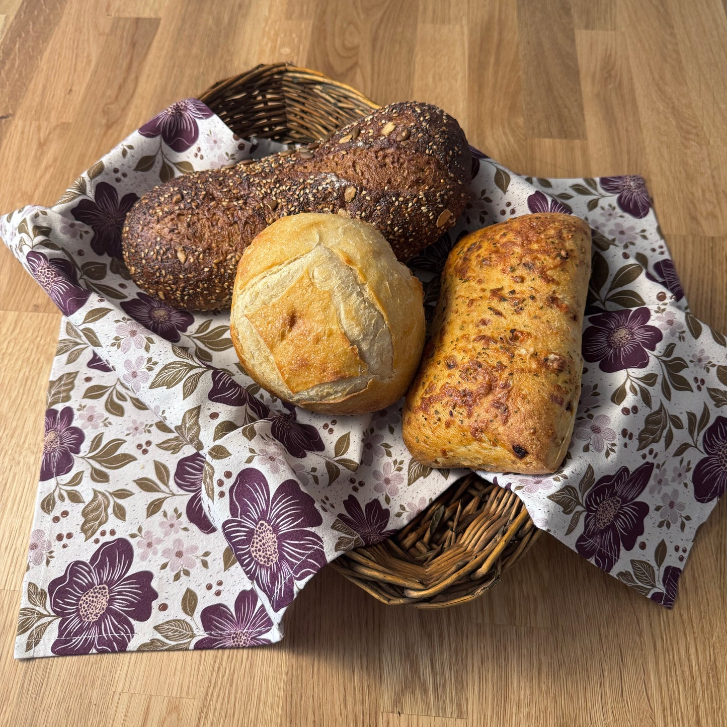 Basket of bread on a floral-patterned cloth on a wooden surface