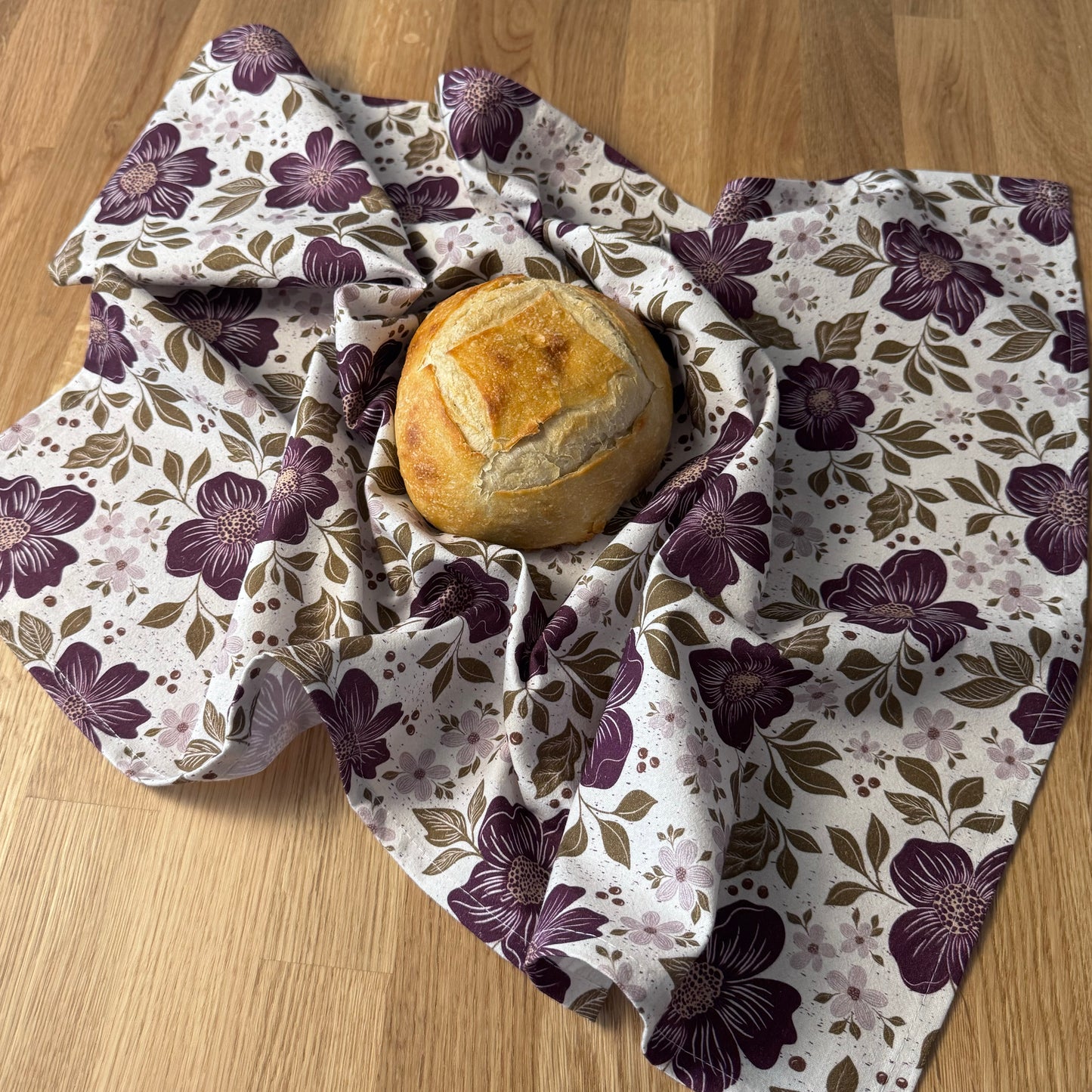 Bread roll wrapped in a floral-patterned cloth on a wooden surface