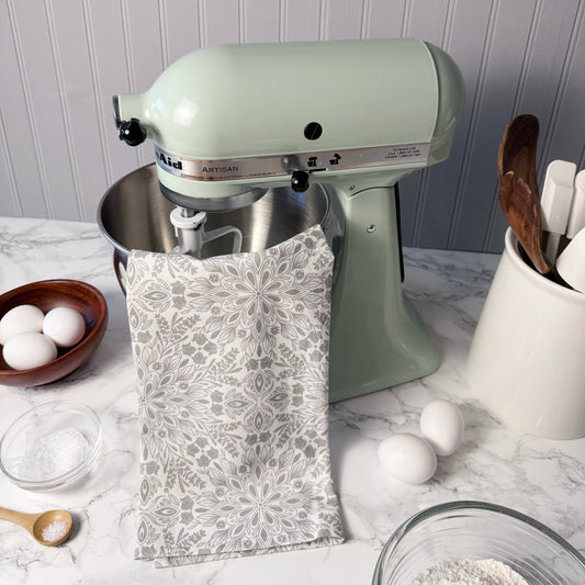 Kitchen stand mixer on a kitchen counter with eggs, flour, and utensils.