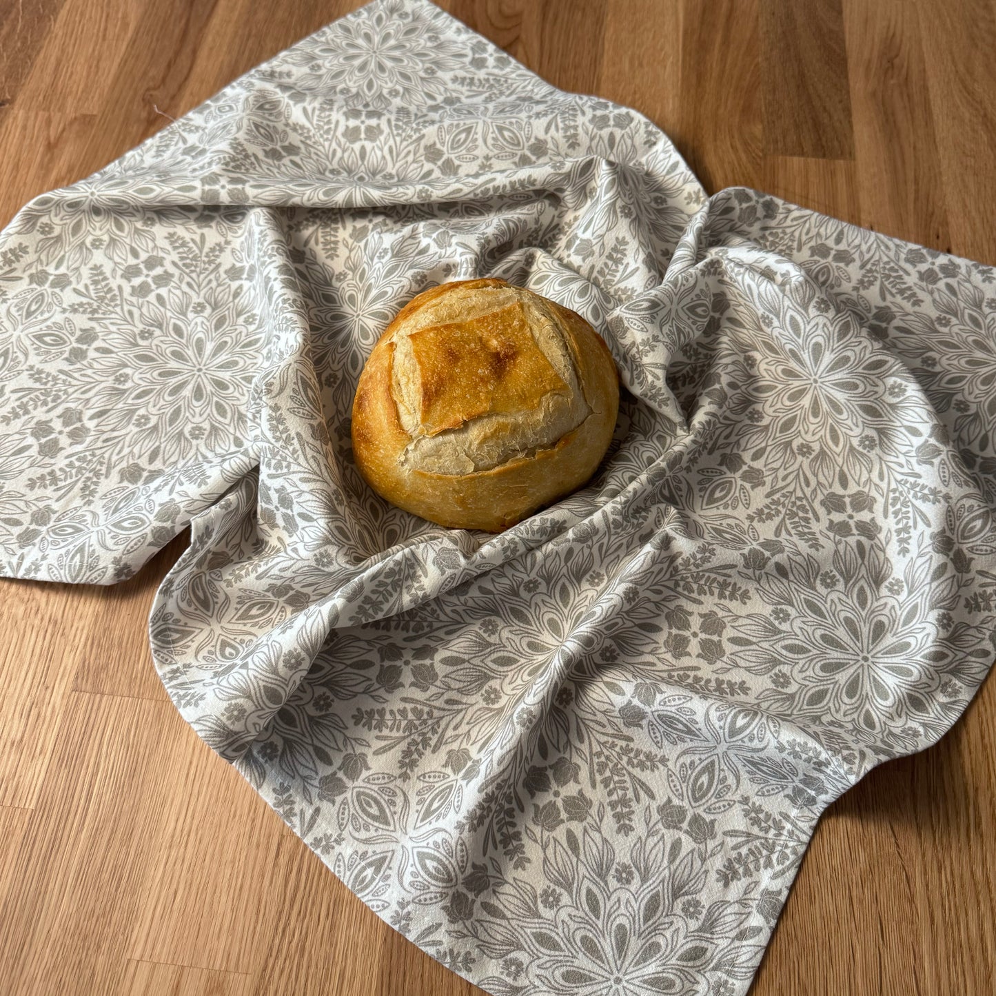 Loaf of bread wrapped in a patterned cloth on a wooden surface