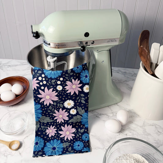 Kitchen scene with a light green stand mixer, floral towel, and kitchen utensils on a white countertop.