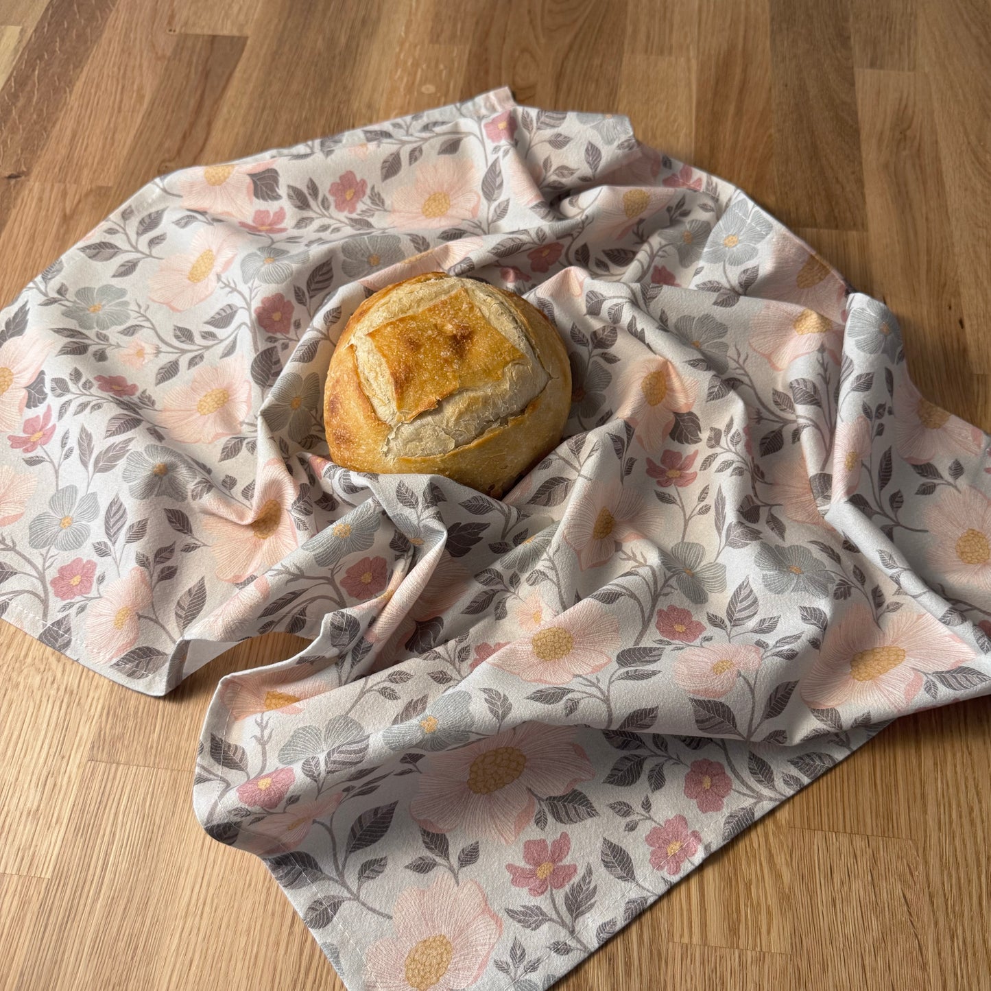 Loaf of bread wrapped in a floral-patterned cloth on a wooden surface