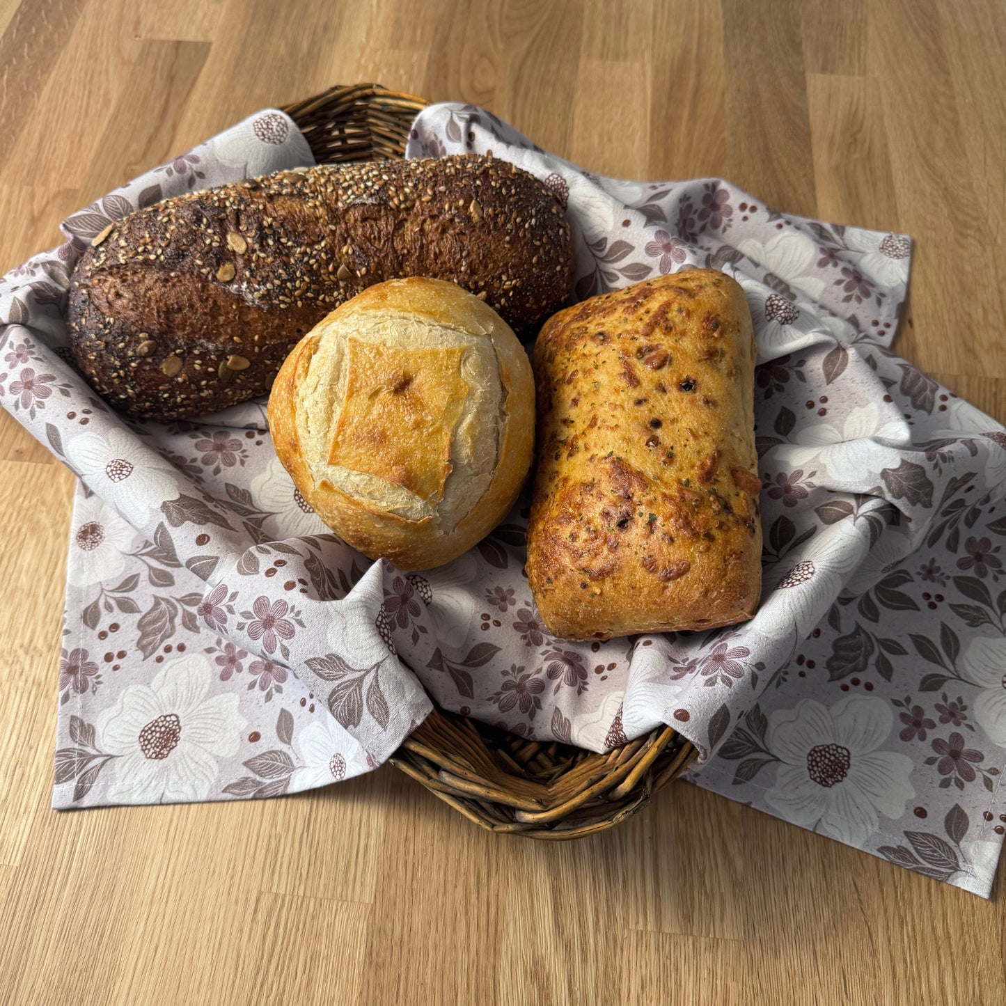 Basket of bread on a wooden table with floral-patterned paper