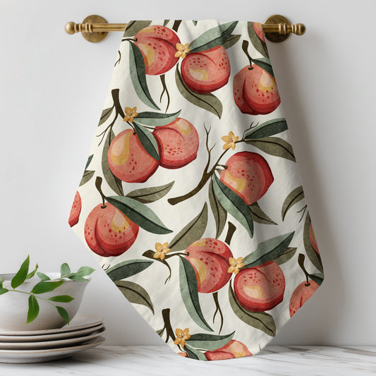 Hand-painted peach tea towel featuring ripe peaches, green leaves, and delicate blossoms on a soft cream background.