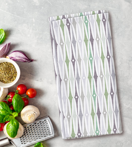 Patterned kitchen towel on a surface with vegetables and a grater.