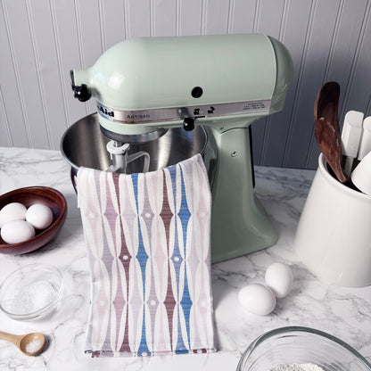 Kitchen stand mixer with a towel draped over it on a kitchen counter.