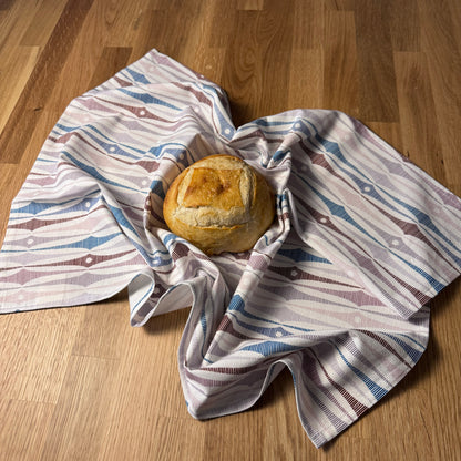 Loaf of bread wrapped in a striped cloth on a wooden surface