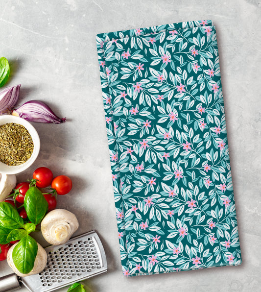 Floral patterned towel on a kitchen counter with vegetables and a grater.