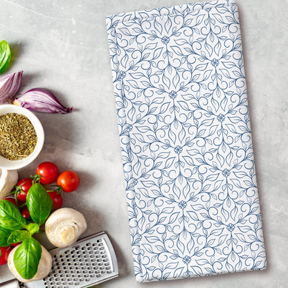 Floral patterned towel on a kitchen counter with vegetables and a grater.