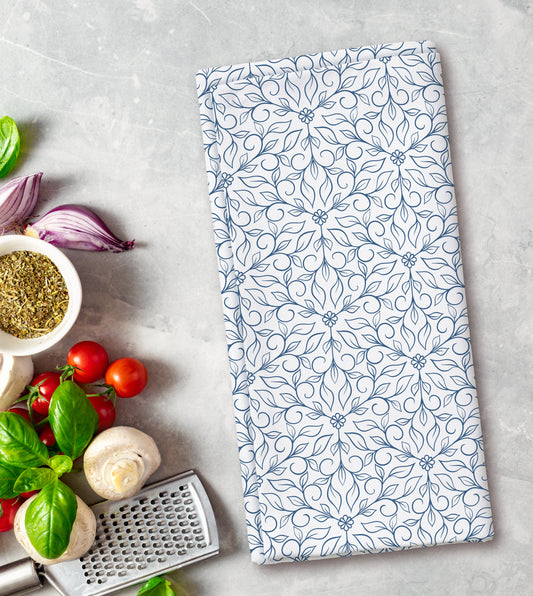Floral patterned towel on a kitchen counter with vegetables and a grater.