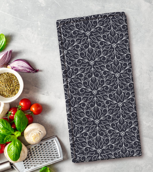 Floral patterned towel on a kitchen counter with vegetables and a grater.