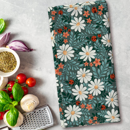 Floral patterned towel on a kitchen counter with vegetables and a grater.