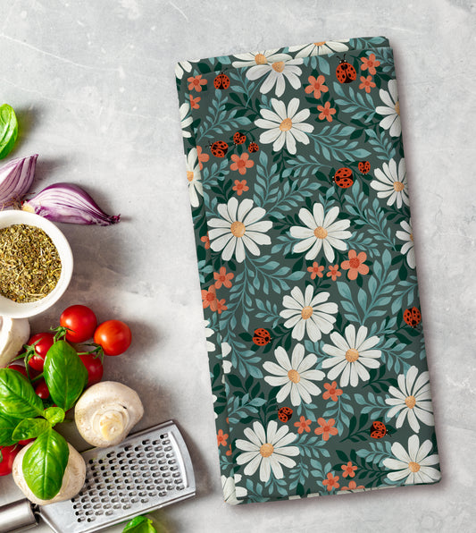 Floral patterned towel on a kitchen counter with vegetables and a grater.