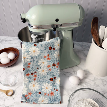 Kitchen scene with a green stand mixer, floral towel, and kitchen utensils on a marble countertop.