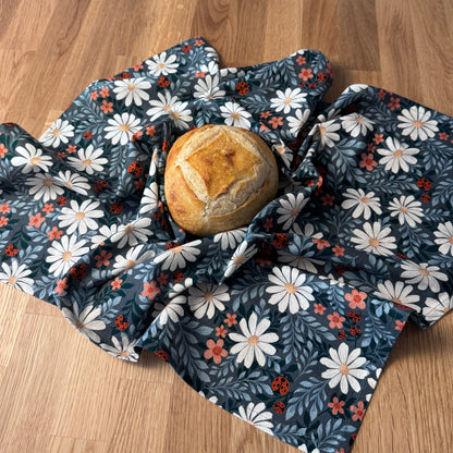 Bread wrapped in a floral-patterned beeswax wrap on a wooden surface