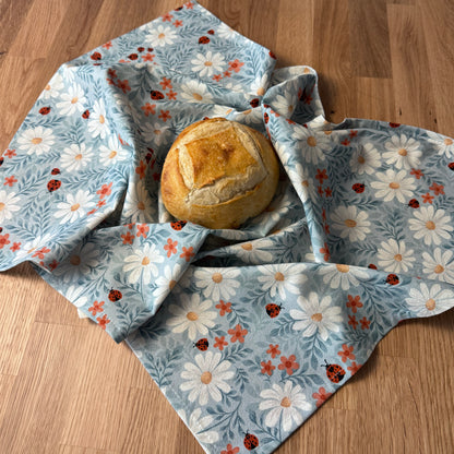 Bread wrapped in a floral-patterned cloth on a wooden surface