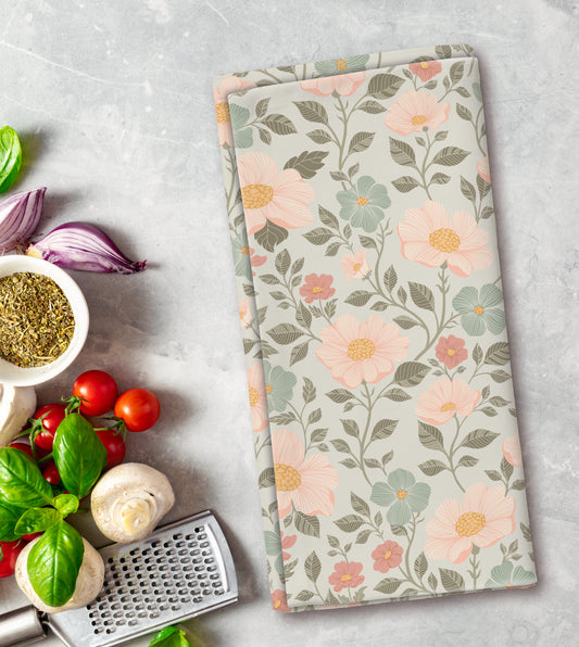 Floral patterned towel on a kitchen counter with vegetables and a grater.