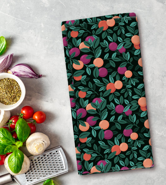 Kitchen towel with fruit pattern on a countertop with vegetables and a grater.
