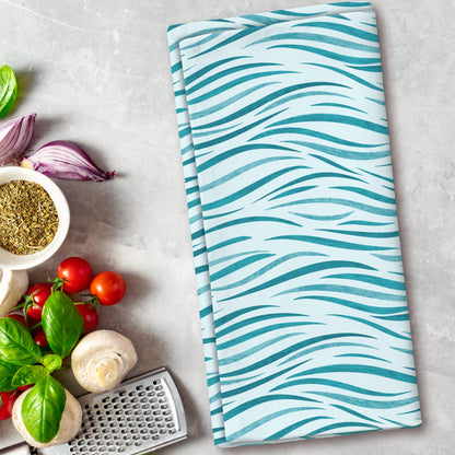 Teal and white patterned towel on a kitchen counter with vegetables and a grater.