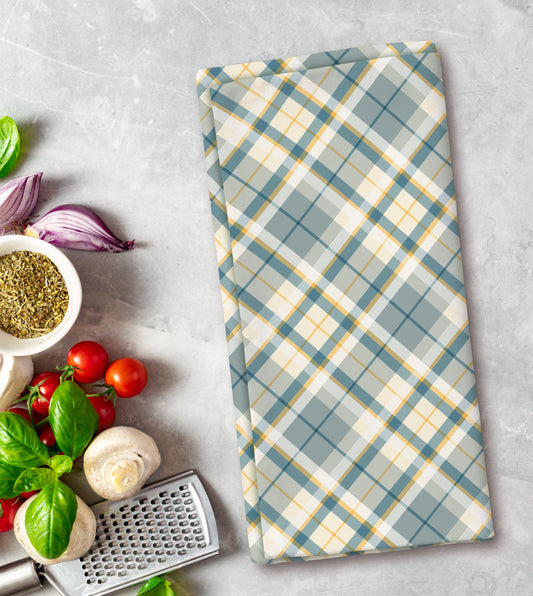 Plaid towel on a kitchen counter with vegetables and a grater