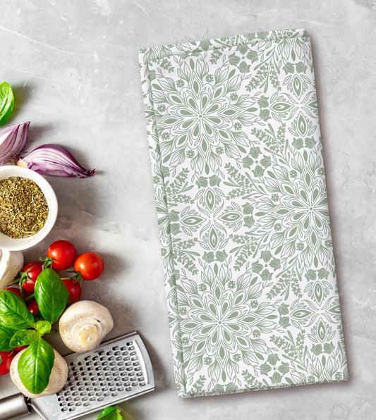 Floral patterned kitchen towel on a gray surface with fresh herbs and vegetables.