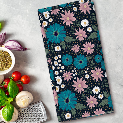 Floral patterned towel on a kitchen counter with vegetables and a grater.