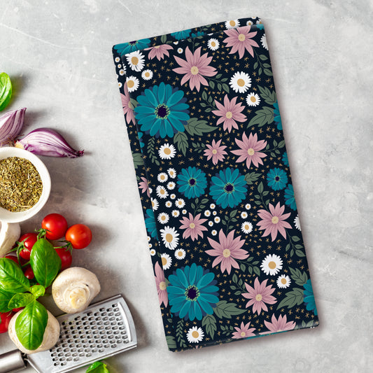Floral patterned towel on a kitchen counter with vegetables and a grater.