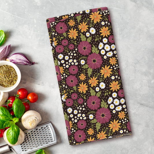Floral patterned towel on a kitchen counter with vegetables and a grater.