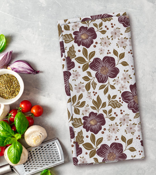 Floral patterned towel on a kitchen counter with vegetables and a grater.